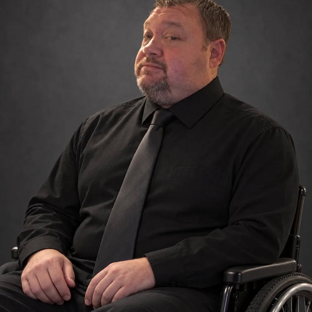 Brian Beaty, founder and owner of Top Search SEO, smiling in his wheelchair in a professional studio portrait